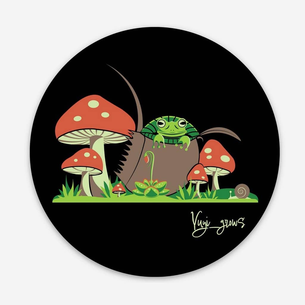 A black, circular sticker with a frog peeking out of a carnivorous plant. There are mushrooms, grass, and a snail surrounding the frog